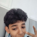 A person taking a selfie and holding up a peace sign with their hand.