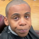 Young person with a buzz cut looking directly at the camera with a skeptical and unimpressed facial expression.