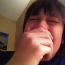 Person covering their face with their hand while crying or laughing intensely.