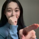 Young woman pointing her finger at the camera while shyly covering her mouth with her other hand.