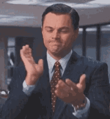 Leonardo DiCaprio in a suit performing a slow, sarcastic clap.