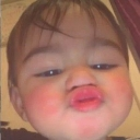 Baby making an exaggerated, close-up pouting face with puckered lips.