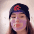 A girl wearing a black beanie with a red logo performs a dramatic spit take using a purple liquid filter.
