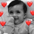Baby smiling with red heart emojis surrounding their face.
