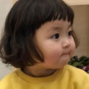 A young girl with a bob haircut wearing a yellow shirt looking sideways with a skeptical and judging expression.