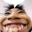 A person's face shown in extreme close-up with fish-eye lens distortion, highlighting a wide, toothy grin.