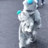Fuzzy gray mascot character walking while holding a smaller matching plush toy.