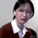 A person making a disgusted and confused facial expression while wearing white earbuds.