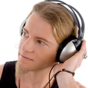 A man with long hair wearing silver and black headphones looking off to the side.