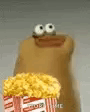 A brown puppet character holding a bucket of popcorn and staring blankly.