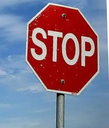 A standard red octagonal stop sign with white text against a blue sky background.