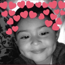 A smiling child with dimples wearing a digital filter of pink hearts around their head.