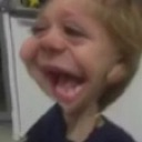 Child with a heavily distorted face and an exaggerated wide-open mouth laughing.