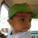 Toddler wearing a green cap looking sideways with a skeptical expression.