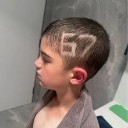 A young boy in profile view displays a buzz cut with the number 67 shaved into the side of his head.