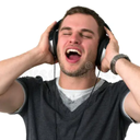 A man with his eyes closed wearing headphones and singing with his mouth wide open.