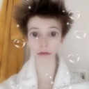 Person with wide eyes and a distorted face surrounded by floating hearts and bubbles.