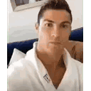 Cristiano Ronaldo in a white bathrobe gradually smiles and raises a cup to the camera.