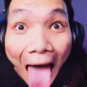 A person with wide eyes sticking their tongue out while wearing headphones.