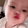 Toddler puckering their lips for a kiss in a repetitive motion.