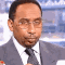Stephen A. Smith wearing glasses and a suit, looking down with a heavy, disappointed sigh.