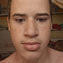 Young man staring directly at the camera with a neutral and intense expression.