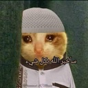 Crying cat wearing a white kufi and thobe with Arabic text overlay.