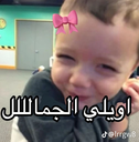 A toddler with a mischievous grin wears a digital pink bow filter with Arabic text overlay.