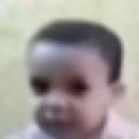 A blurry, low-resolution face of a child looking with a deadpan, confused expression.