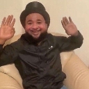 Man wearing a top hat smiling with both hands raised in the air.