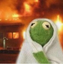 Kermit the Frog wearing a white blanket with a blurry house fire in the background.
