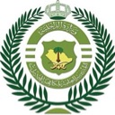 Saudi Arabian government emblem featuring a shield with a palm tree and crossed swords, surrounded by a laurel wreath and to…