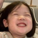A young child with a wide, toothy grin and eyes squeezed shut in laughter.