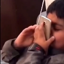 A person holding a smartphone tightly against their ear with an intense, focused expression.