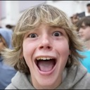 A young boy with blonde hair looking directly at the camera with a wide-open mouth and shocked expression.