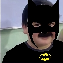 Child wearing a poorly edited Batman mask looking directly at the camera with a serious expression.