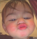 Baby with a close-up, distorted face puckering their lips for a kiss.